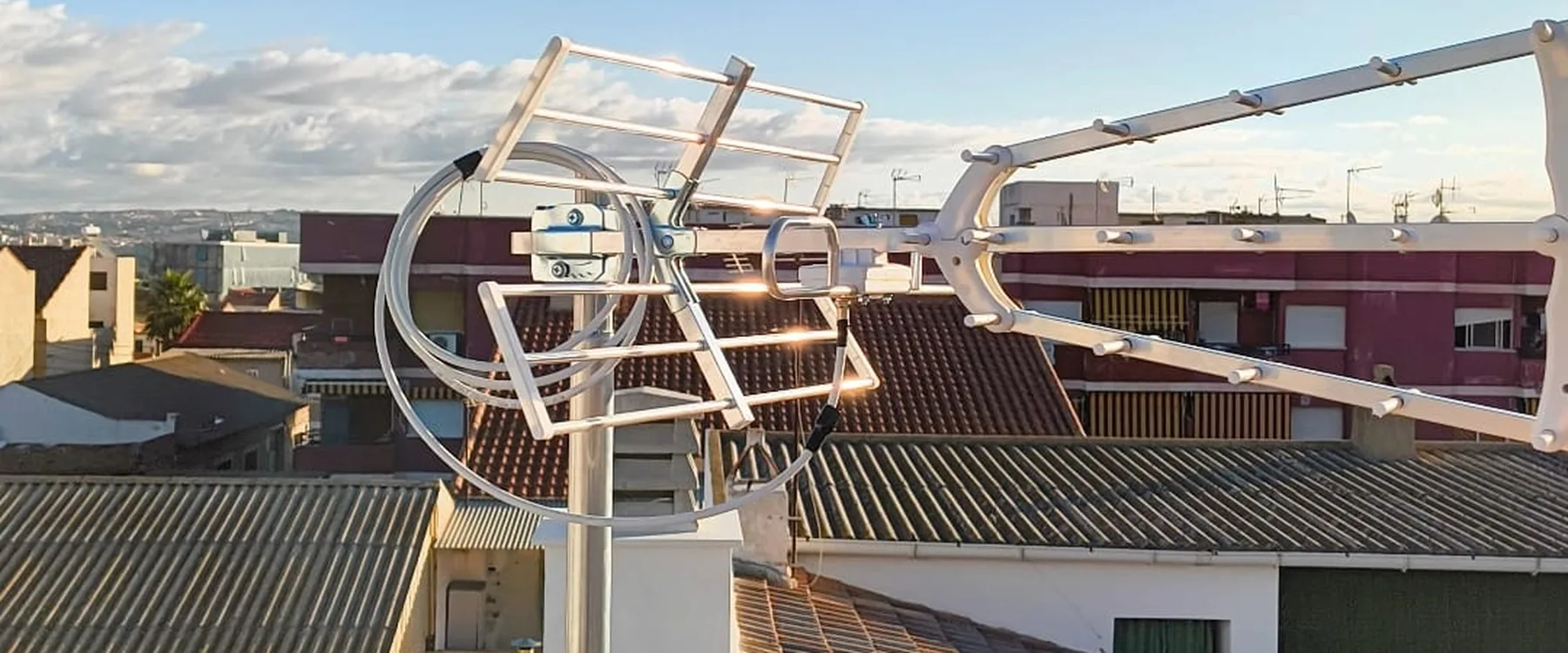 Antena de televisión UHF y dipolo de FM montados sobre mástil en el tejado, con los tejados de Las Torres de Cotillas al fondo